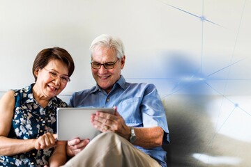 Senior couple using a digital device in a living room