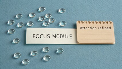Modern workspace concept with focus module note and clear glass pebbles on a soft blue background for productivity enhancement