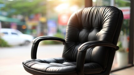 Comfortable black leather office chair placed near a window with soft sunlight filtering through in a modern workspace