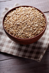 Uncooked Whole Oats in Beige Bowl on Wooden Background Close Up