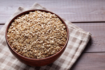 Uncooked Whole Oats in Beige Bowl on Wooden Background Close Up