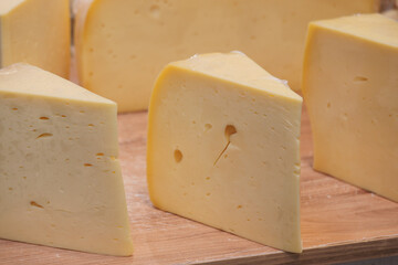 Cheese on a wooden board cut into triangular pieces