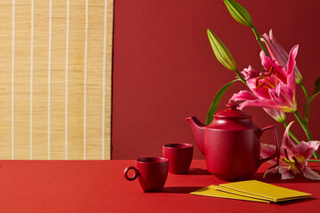 A clean Lunar New Year scene with red tea accessories, flowers, and traditional decor. Designed for product presentation, banner design, festive branding. Content for end-of-year celebrations.