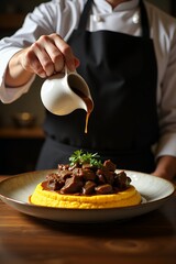Chef Drizzling Sauce Over Gourmet Dish with Polenta and Meat.