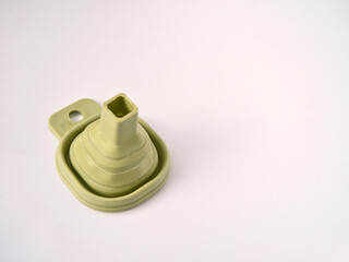 A flexible green rubber folding funnel isolated on a white background. A practical contemporary household item.