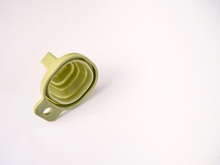 A flexible green rubber folding funnel isolated on a white background. A practical contemporary household item.
