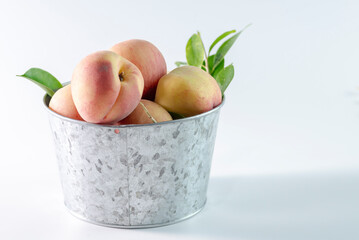 A metal bowl with fresh peaches 