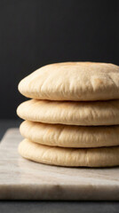Stack of fresh homemade pita bread on a marble surface with soft natural lighting, showcasing simple, clean, and artisanal bakery style