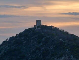 historic tower casts shadows at dusk, warm illumination highlights aged stone and turret shape © Nataliia