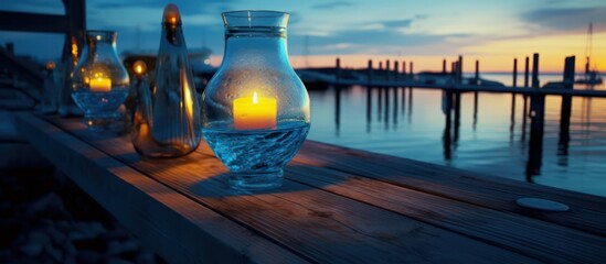 Candlelit lanterns on a wooden dock at sunset over a calm marina.