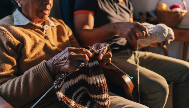 Close-up of a senior woman's hands knitting a warm scarf while a family member assists, showcasing a traditional hobby and intergenerational bonding