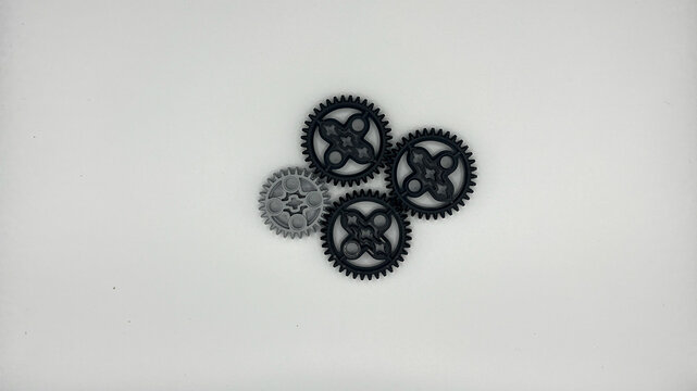 Group of black and gray plastic toy gears arranged together on white background, teamwork and mechanics concept