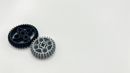 Black and gray plastic toy gears isolated on white background with copy space, mechanical concept