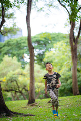 Little asian Thai school boy enjoy running on green meadow grass city park building
