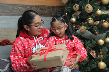 Latina single mom with her 4-year-old brunette daughter wearing glasses, dressed in ugly sweaters,...