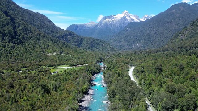 Hornopiren, Chile: Aerial footage of bridge and road by Rio Blanco surrounded by forest with mountain in the background in Hornopiren,  Chile's Los Lagos region along the Carretera Austral