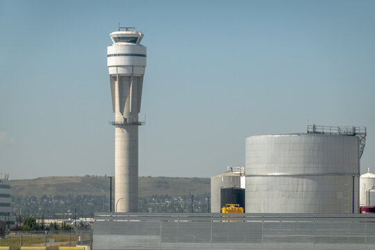 Calgary, Alberta, Canada. Nov 27, 2025. The distinct, modern NAV CANADA air traffic control tower at Calgary International Airport (YYC) stands tall beside large airport fuel storage tanks.