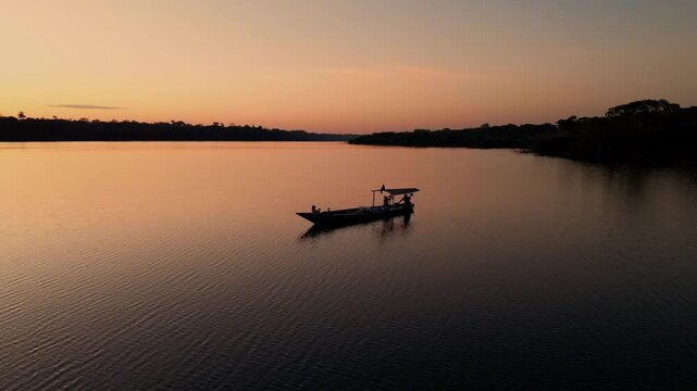 Drone video of Lake Valencia at sunset, featuring smooth aerial views of golden reflections, tropical rainforest landscape, and serene Amazonian atmosphere in Madre de Dios, Peru