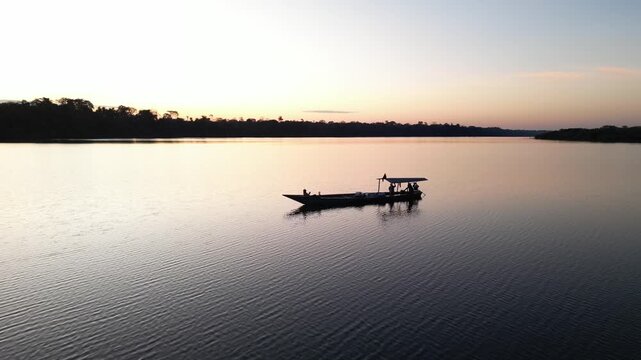 Drone video of Lake Valencia at sunset, featuring smooth aerial views of golden reflections, tropical rainforest landscape, and serene Amazonian atmosphere in Madre de Dios, Peru