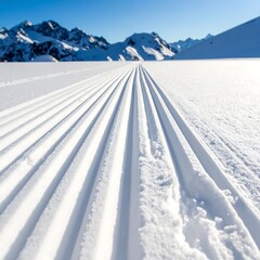 Freshly groomed tracks in snowy landscape with mountain range