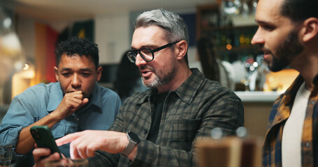 Fototapeta premium Smartphone, people and friends in pub, talking and social media with communication. Men, mobile user and cellphone with internet, connection and digital app with website information and conversation