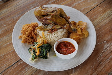 Asian lunch menu, white rice, fried chicken with chili sauce, complete with steamed vegetables served on a plate in a restaurant