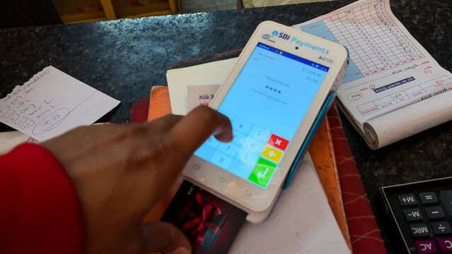 customer entering pin on sbi payments card swipe machine at retail counter