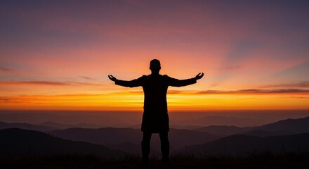 Silhouette of man with arms outstretched on mountain top at sunrise. Person celebrating freedom and success while watching scenic landscape. Spirituality and hope concept