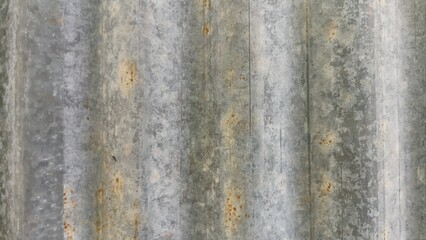 Old corrugated galvanized metal sheet texture with scattered spots and streaks of brown rust covering the gray surface