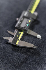 A detailed close-up of a MITUTOYO ABSOLUTE AOS vernier caliper, showcasing its precision stainless-steel body, digital measurement display, and finely machined scale. The tool represents high-accuracy