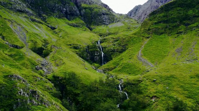 Picturesque waterfalls cascade down the lush green mountains in glencoe, scotland