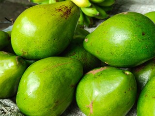 Fresh green and yellow avocados displayed at a traditional market, ideal for food promos, agriculture content, market scenes, and educational materials about tropical fruits.