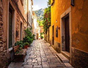 Obraz premium Stone-paved alleyway with buildings, plants, and a glimpse of the mountains