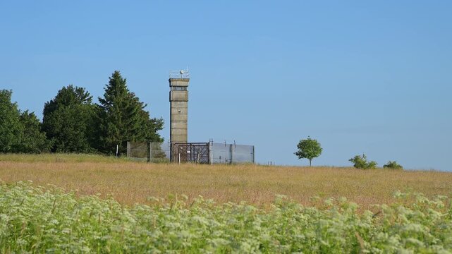 Wachturm der ehemaligen Innerdeutsche Grenze neben gr&uuml;nem Baum und Wiesen, Sommer, Fladungen, Frankenheim, Hohe Rh&ouml;n, Rh&ouml;n, Hessen, Th&uuml;ringen, Bayern, Deutschland, Europa