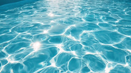 Sunlight reflects off the surface of a sparkling blue swimming pool creating a beautiful display of light and water. The day is clear and bright perfect for swimming.