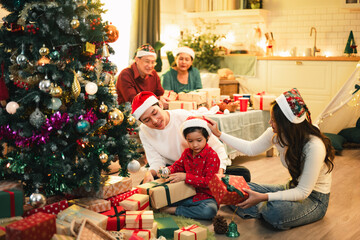 family, christmas, happy family, families, celebration, A joyful multigenerational Asian family exchanging Christmas gifts beside a decorated tree, creating a warm and festive holiday atmosphere.