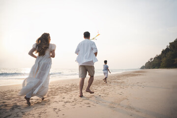 family, vacation, beach, happy family, holiday, asian, fun, happy, A joyful family runs along the beach at sunset, enjoying quality time together in a relaxing vacation atmosphere © Garun Studios