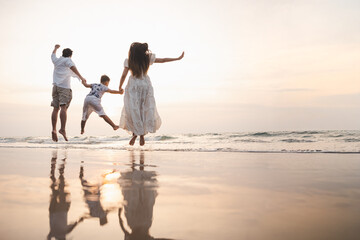 Fototapeta premium family, vacation, beach, happy family, holiday, asian, fun, happy, A happy family jumps together on the beach at sunset, enjoying a joyful and relaxing vacation moment.