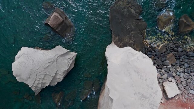 Perfect top-down aerial drone view flying over an iconic volcanic rock formation in the deep blue Atlantic Ocean near the fishing port of San Miguel de Tajao, Tenerife, Spain.