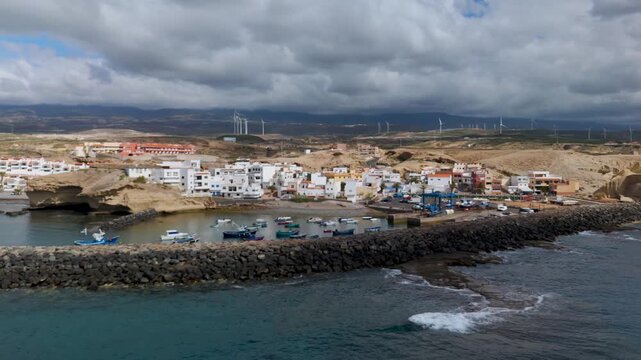 Aerial drone shot panning across the colorful houses and small fishing harbor of San Miguel de Tajao, Arico, Tenerife, Canary Islands, Spain.