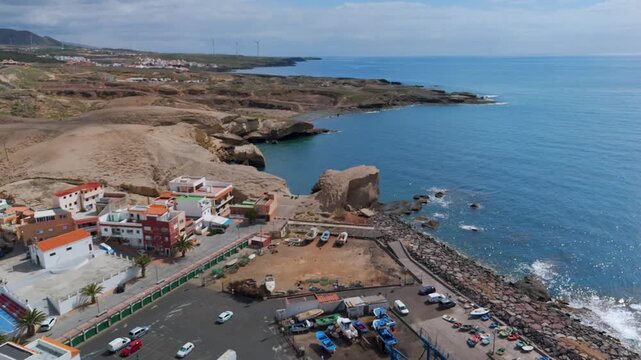 Spectacular aerial drone shot moving away from the vibrant fishing port and coastal houses of San Miguel de Tajao, Tenerife, Canary Islands.