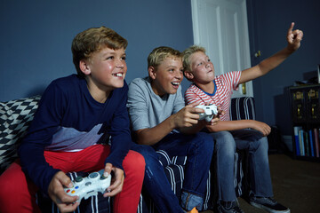Gaming, challenge and teens on sofa in home with friends, playing and online entertainment. Contest, living room and boys with controller for video games, esports and winning on weekend together