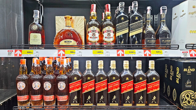 A display of various liquor bottles on shelves, featuring prominent brands and differing packaging designs. Thailand, November 28, 2025