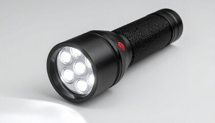 Black LED flashlight on light gray surface.