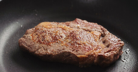 Closeup shot of ribeye steak frying on non stick pan