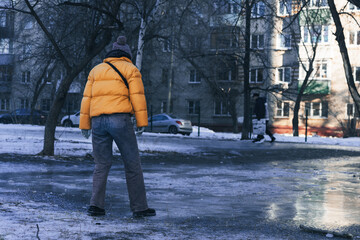 Naklejka premium A young woman walks cautiously along an icy street on a winter day for fear of slipping and falling. showing danger of winter ice and the risk of slipping on a frozen surface.