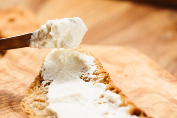 spreading ricotta cheese on fresh rustic bread