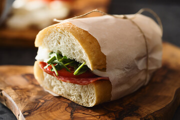 ciabatta sandwich with salami and mozzarella cheese on walnut table
