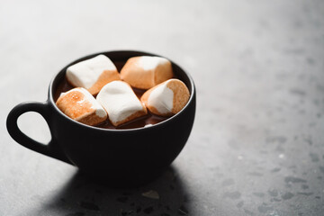 cup of hot chocolate with marshmallow on terrazzo background