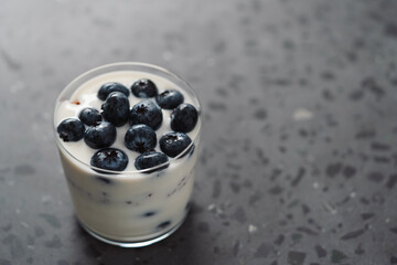 greek yogurt with blueberries and granola in glass on concrete background